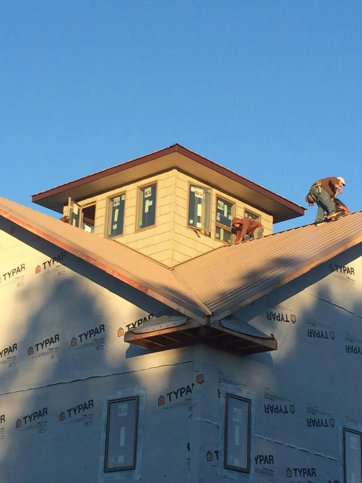 Roofers working around a rooftop cupola on a new metal roof at sunset — Roof Waterproofing in Millwood by Roofing Brothers